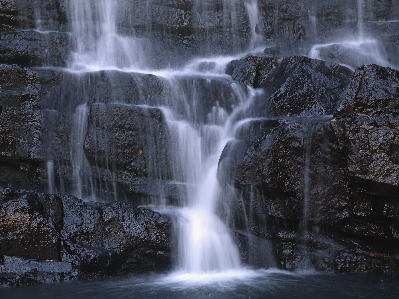 Silky long-exposure curtain of Elephant Falls over dark rock, Shillong