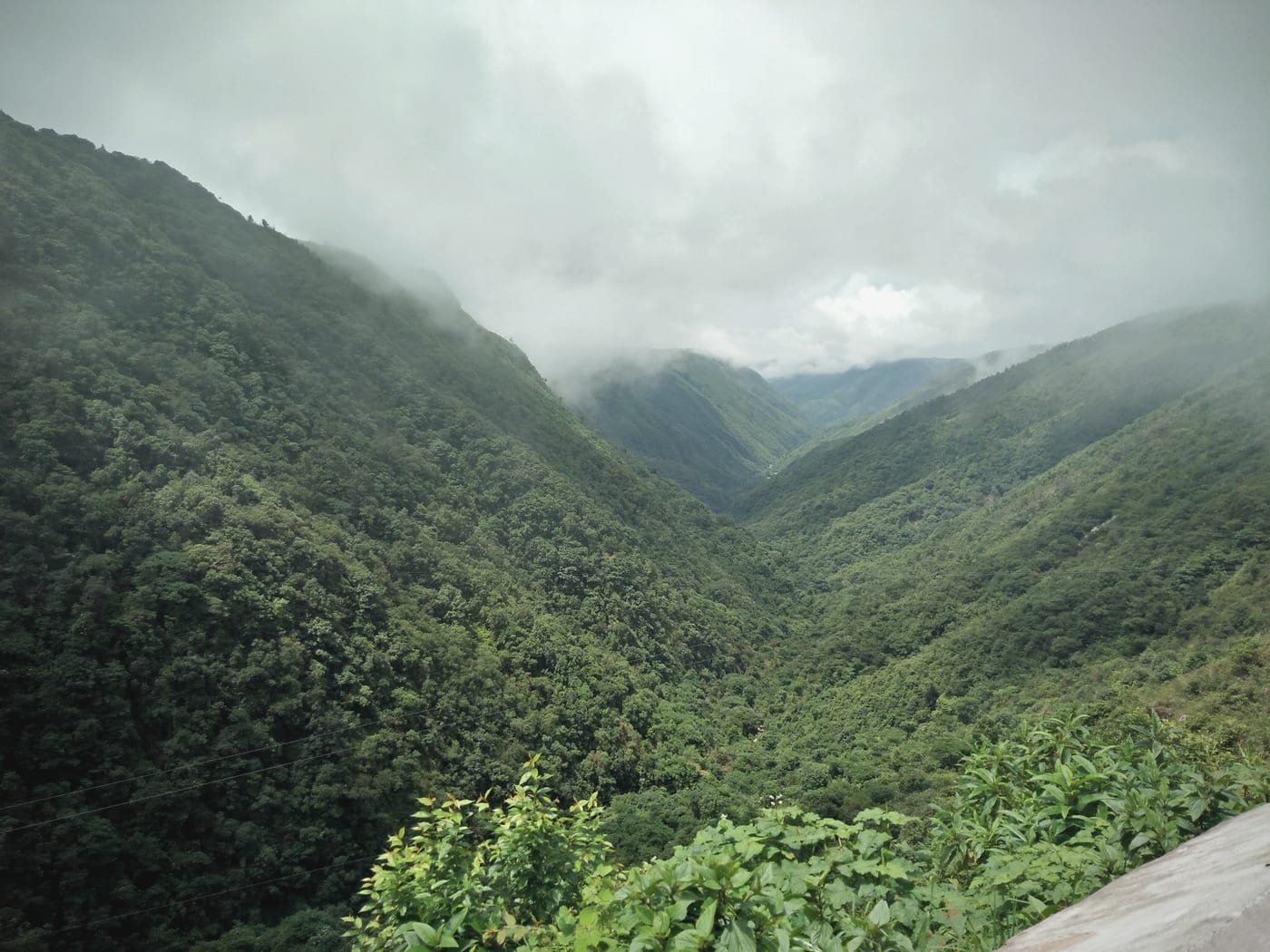 Monsoon clouds pouring through the green V of Mawkdok Dympep Valley on the Shillong–Sohra road