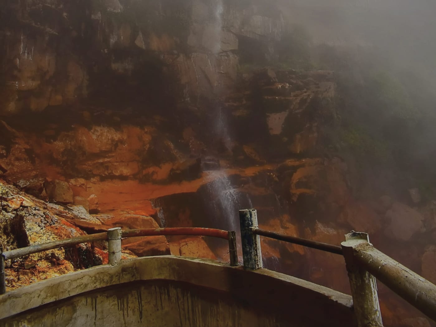 Wahkaba Falls appearing out of dense monsoon fog beside the viewpoint railing, Cherrapunji